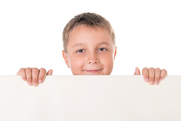 Adolescente varón guapo sonriente posando detrás del panel blanco