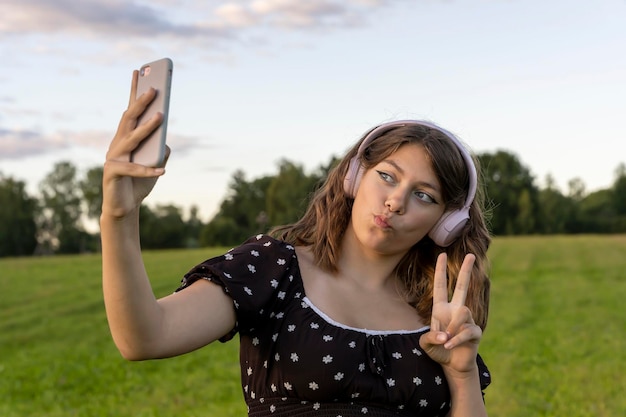 Una adolescente con vestido escucha música en un teléfono inteligente