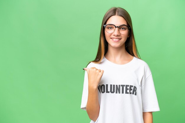 Adolescente voluntaria chica caucásica sobre antecedentes aislados apuntando hacia un lado para presentar un producto