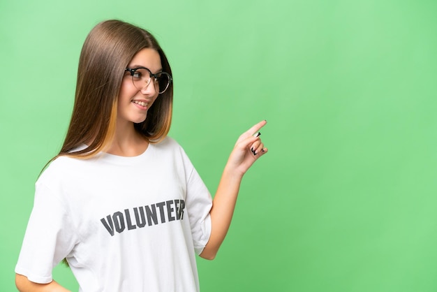 Adolescente voluntaria chica caucásica sobre un fondo aislado señalando con el dedo hacia un lado y presentando un producto