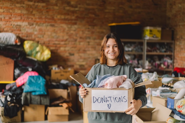 Foto adolescente voluntário preparando caixas de doação para pessoas doação de roupas para refugiados apoio às vítimas da guerra conceito de ajuda humanitáriaajudando as pessoas