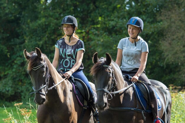 Foto adolescentes a cavalgar contra árvores.