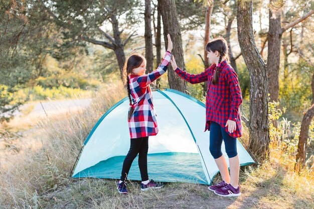 Adolescentes alegres estão satisfeitas com o trabalho feito e se cumprimentam. Vamos acampar