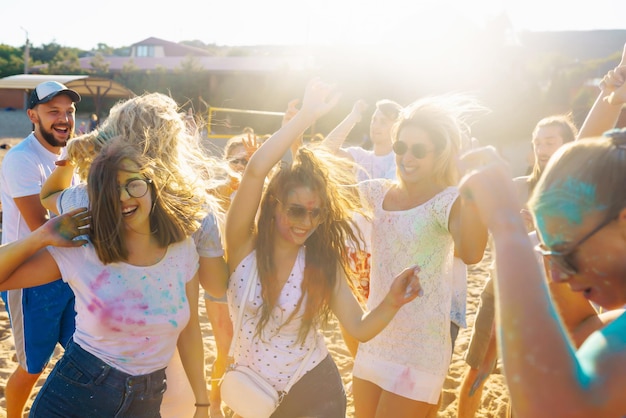 Adolescentes amigos se divierten en el festival de Holi fiesta en la playa celebrando las tradicionales vacaciones de primavera indias