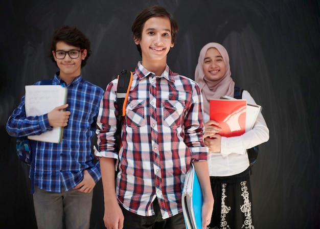 Adolescentes árabes, retrato de grupo de estudantes contra lousa preta usando mochila e livros na escola