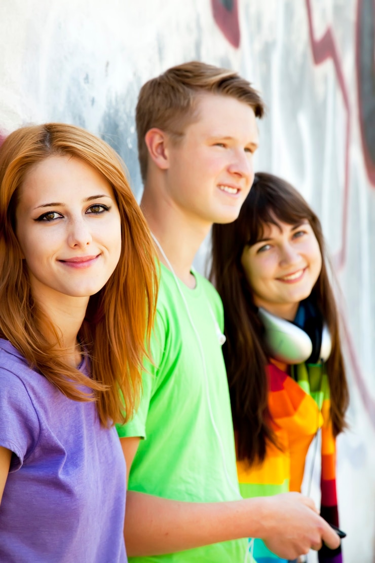 Foto adolescentes con auriculares cerca de la pared de graffiti.