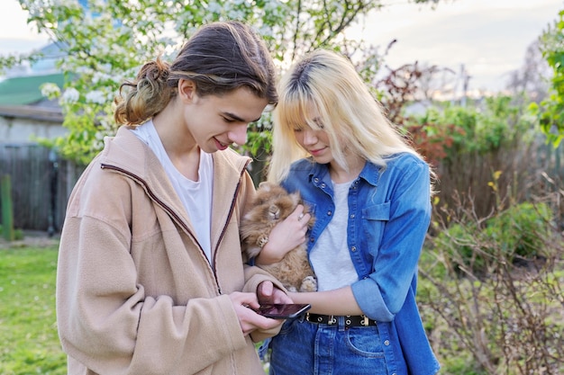 Foto adolescentes com coelho decorativo nas mãos falando e olhando para smartphone