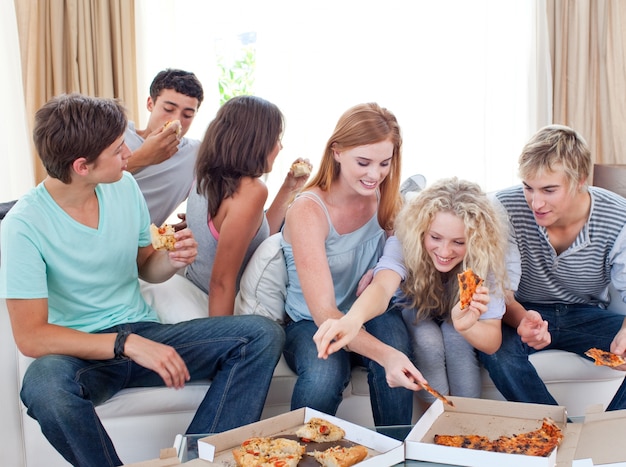 Adolescentes comiendo pizza en casa