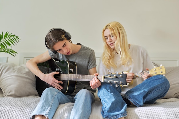 Adolescentes creativos amigos con instrumentos musicales guitarra acústica y ukelele.