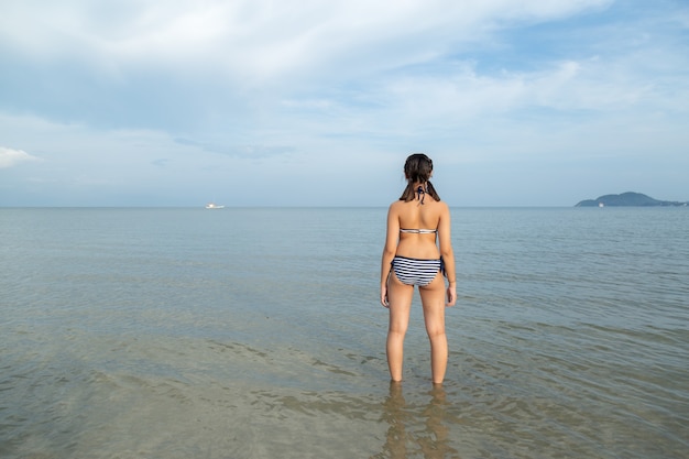 Adolescentes da Ásia usando biquíni na praia com espaço de cópia.