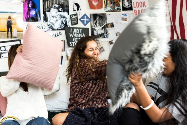 Adolescentes en un dormitorio con una almohada luchan fiesta de pijamas y concepto de infancia