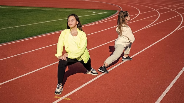 Adolescentes estirándose antes de correr corredores de maratón preparándose para la competencia de carreras sprinter calentando en el estadio gimnasio flexibilidad niños entrenando en la escuela lección de educación física