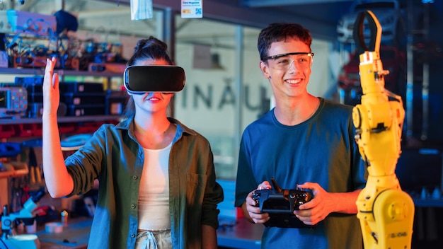 Adolescentes fazendo experimentos em robótica em um laboratório Garoto com óculos de proteção e garota com fone de ouvido VR