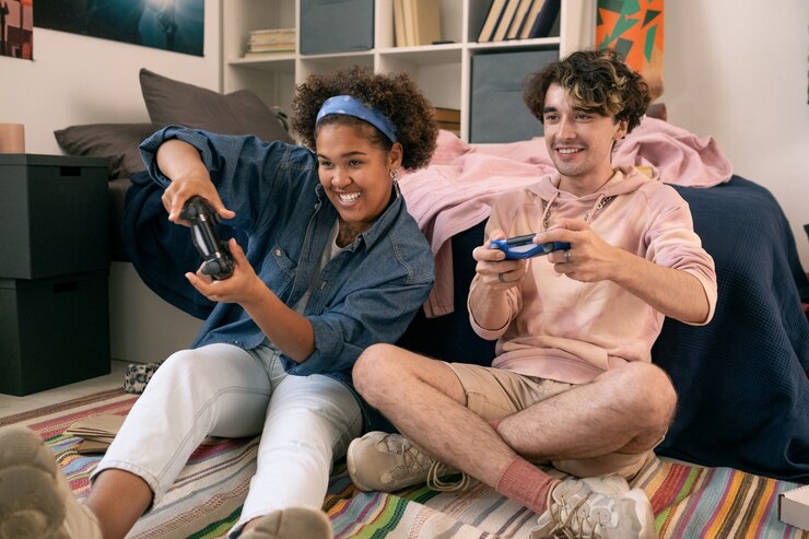Foto adolescentes felizes com joysticks jogando videogame no chão do quarto ao lado da cama