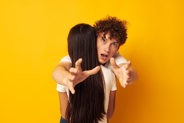 Adolescentes ficam abraçados em camisetas brancas fundo amarelo inalterado