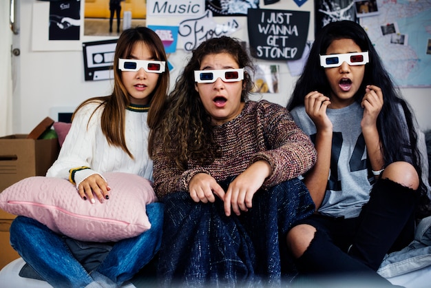 Las adolescentes con gafas de película 3d sorprendieron asustadas y viendo la televisión