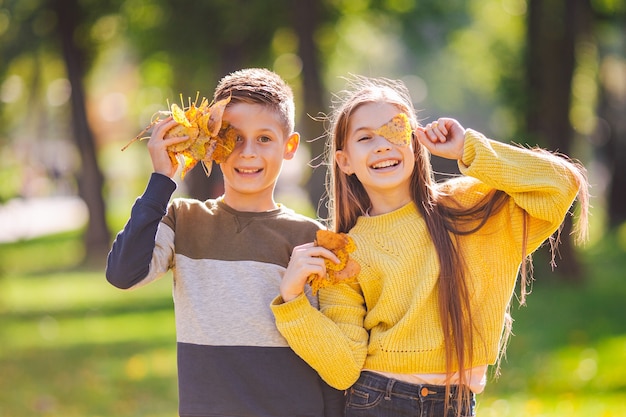 Foto adolescentes gêmeos felizes, menino e menina, posando abraçados no parque outono