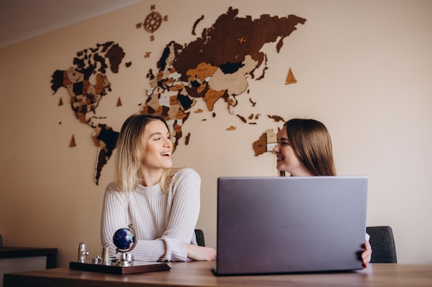 Foto adolescentes hablando y divirtiéndose juntas mientras se sientan cerca de una laptop en el café bar