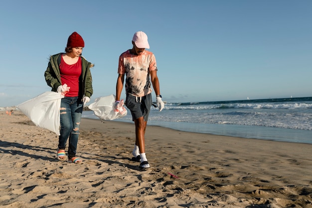 Adolescentes limpiando playa, recogiendo basura trabajo voluntario