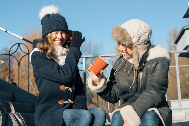 Adolescentes meninas gritam em um copo de papel megafone