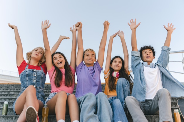 adolescentes meninos e meninas em camisetas coloridas de mãos levantadas encontrando-se Conceito de amizade