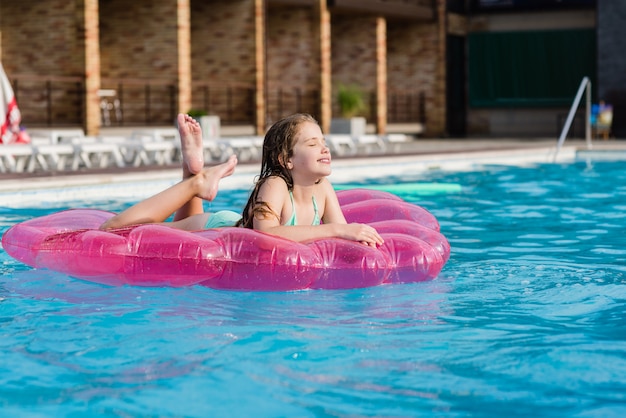 Adolescentes no colchão de ar na piscina