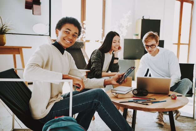 Adolescentes Novos Que Sentam-se Nas Poltronas No Lugar De Coworking.