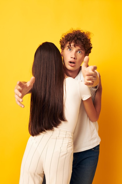 Los adolescentes se paran abrazándose unos a otros en camisetas blancas con fondo amarillo inalterado