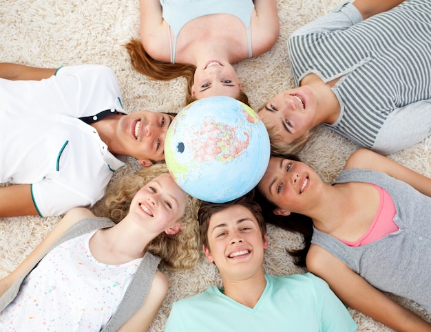 Adolescentes en el piso con un globo terráqueo en el centro