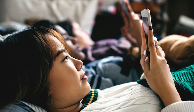 Adolescentes que usan teléfonos inteligentes en una cama de internet en la fiesta de pijamas