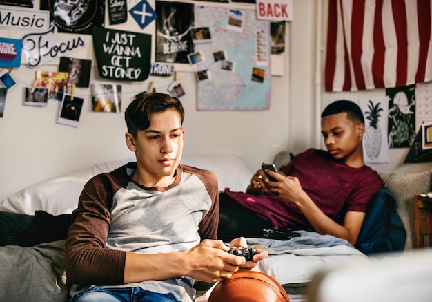 Adolescentes saindo em um quarto jogando videogame e usando um smartphone