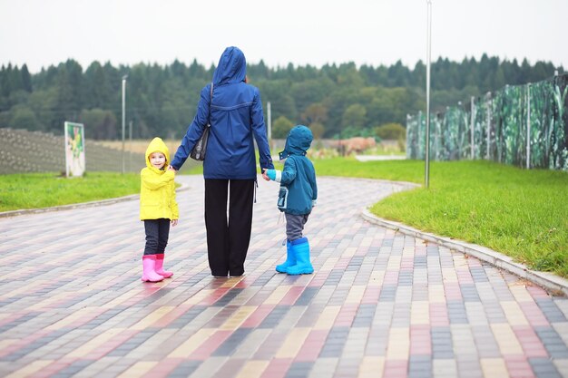 Adopción de paternidad familiar y concepto de personas madre feliz y niños pequeños caminando en el parque de verano