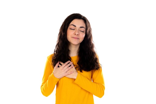 Adorable adolescente con suéter amarillo aislado en una pared blanca