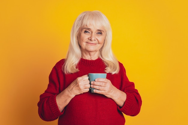 Adorable anciana bebiendo cacao taza caliente aislado sobre fondo amarillo