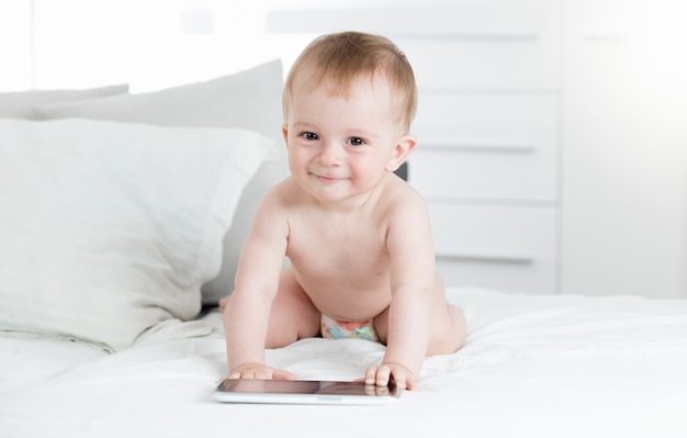 Adorable Baby Boy con tableta digital en la cama