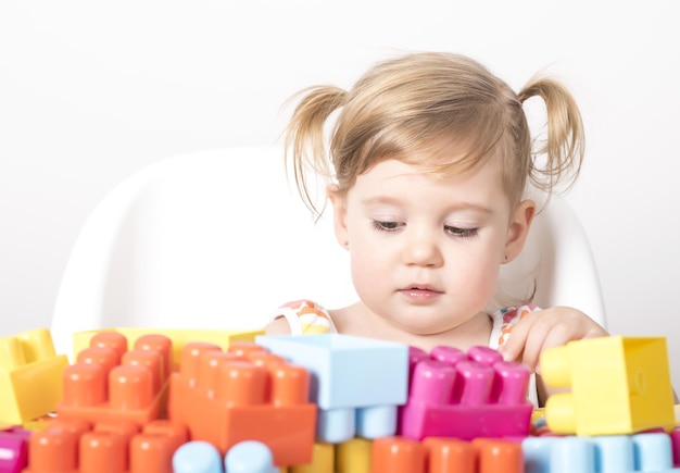 Adorable bebé jugando con juguetes de colores sobre una superficie aislada