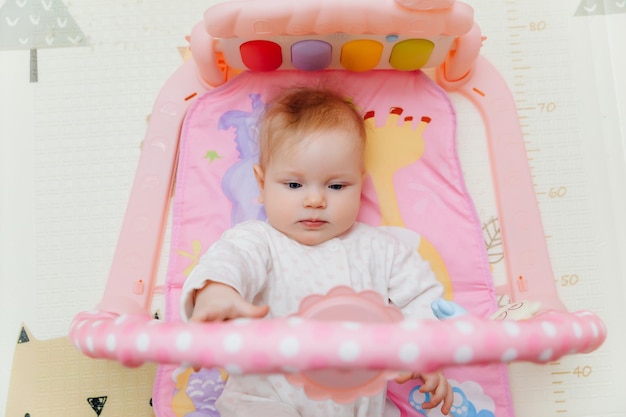 Adorable bebé niño pequeño acostado en una colorida alfombra de juegos para niños con juguetes Espacio para el desarrollo temprano y la actividad del niño bebé 6 meses