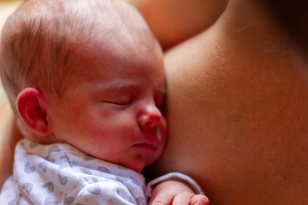 un adorable bebé recién nacido duerme en el pecho de su madre después de amamantar