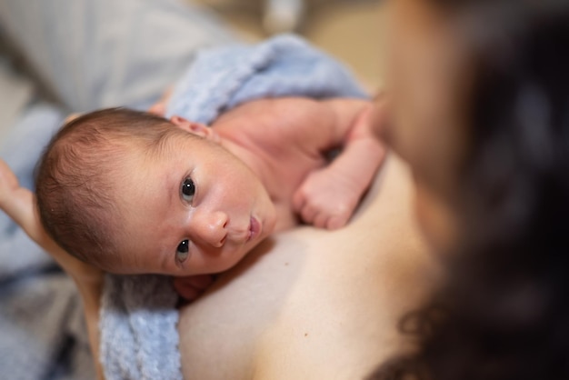 Adorable bebé recién nacido sentado en el pecho de la madre