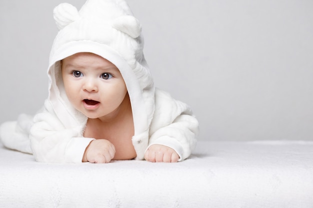 Adorable bebé recién nacido en un traje suave sobre fondo blanco.