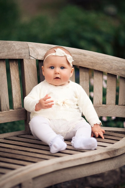 Adorable bebé de seis meses sentado en el banco en el parque