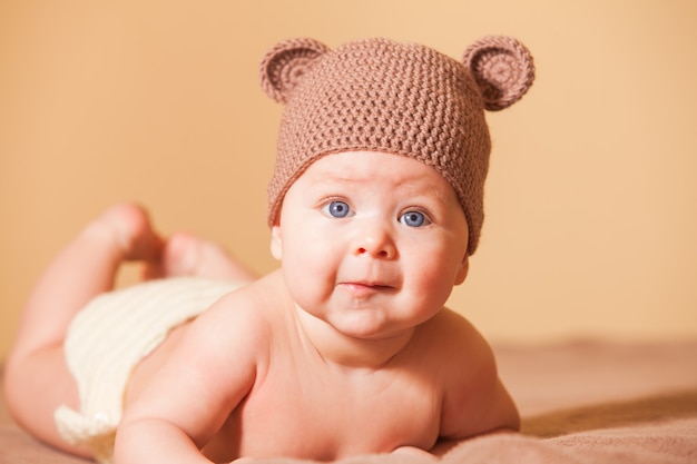 Adorable bebé con sombrero de oso acostado en la cama