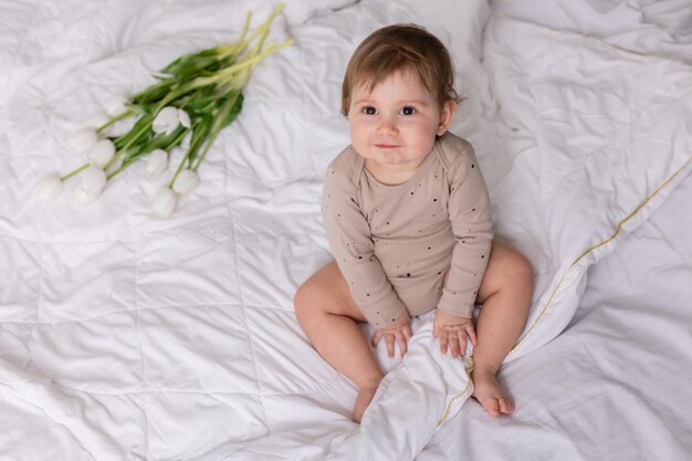 adorable bebé con tulipanes blancos en un espacio de banner de manta para texto