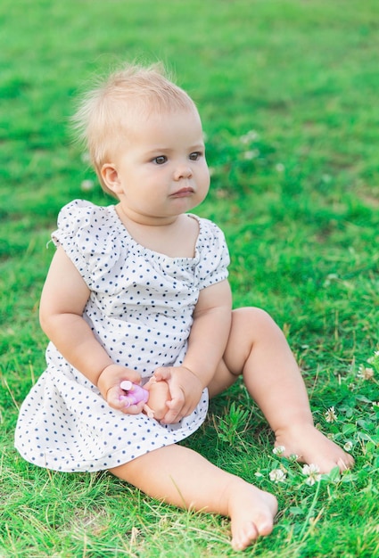 adorable bebé vestido de lunares está jugando con una muñeca en el parque