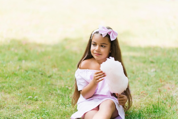 Adorable y bonita niña comiendo algodón dulce blanco niño feliz niño comiendo dulces con emociones en el parque en verano