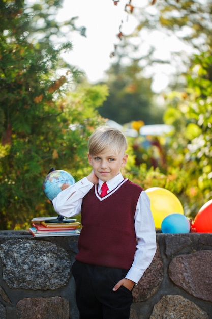 Adorable colegial con libros y globo en el exterior. Educación para niños. Volver al concepto de escuela.