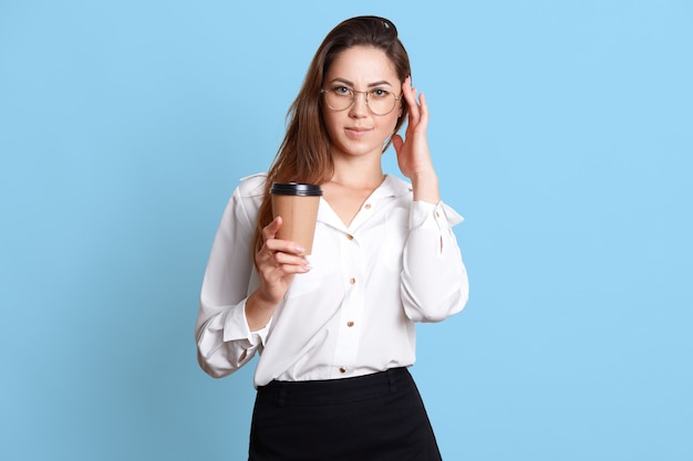 Adorable empresaria en blusa blanca y falda negra con café o té en vaso de papel