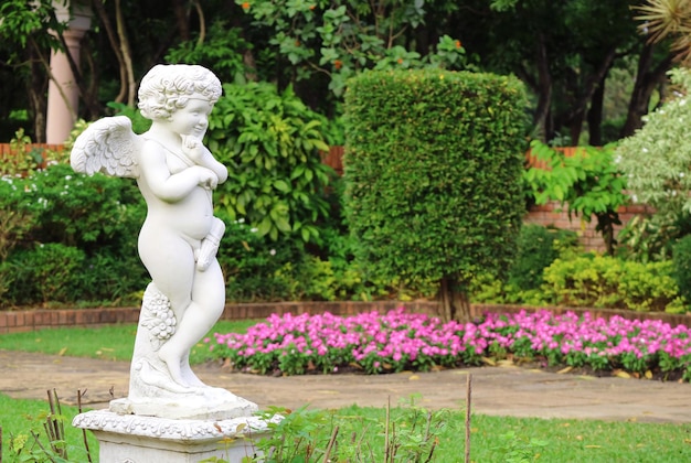 Adorable escultura de cupido en el jardín florido