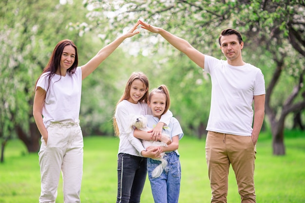 Adorable familia en el floreciente jardín de cerezos en un hermoso día de primavera