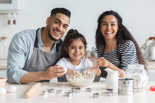 Adorable familia del medio oriente haciendo galletas en casa, interior de la cocina